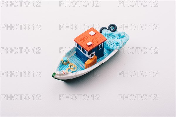 Little colorful model fishing boat placed on white