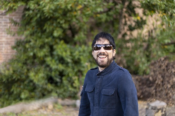 Portrait of a Latino man in a park surrounded by bushes