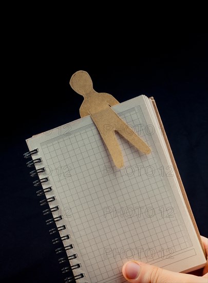 Man shape cut out of paper in notebbok in hand