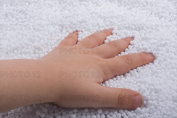 Toddler hand in White polystyrene foam balls as background