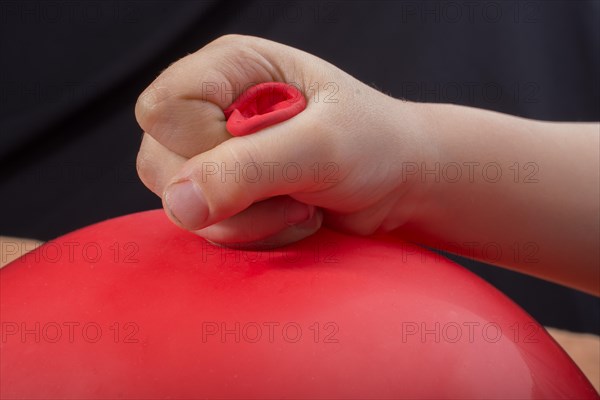 Toddlers hand holding a red balloon in hand