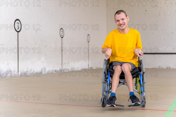 A disabled person in a wheelchair at a Basque pelota game fronton
