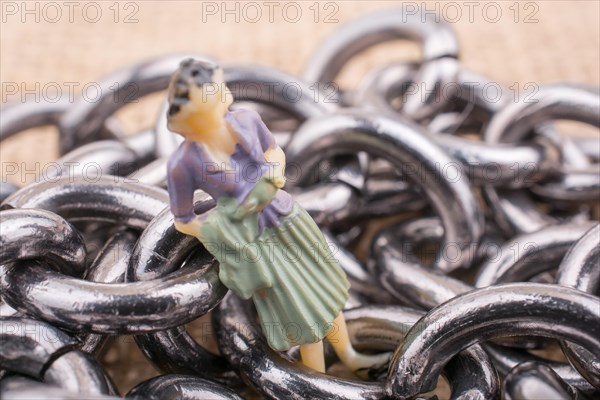 Woman figurine on steel chains on a textured surface on display