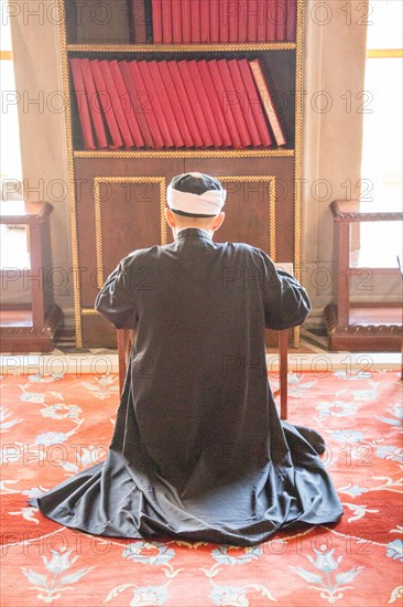 Old man reading Quran in a mosque on display