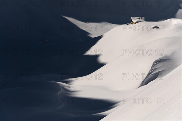 Mountain hut in deep snowy mountain landscape with light and shadow