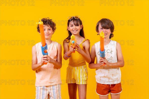 Brothers having fun with water pistols on summer vacations and aiming at camera