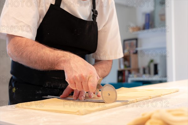 Detail of the hands of a man baking croissants