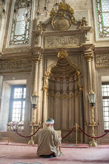 Old man reading Quran in a mosque on display