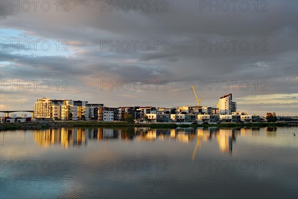 Modern apartment buildings and cranes reflected in the calm Baltic Sea