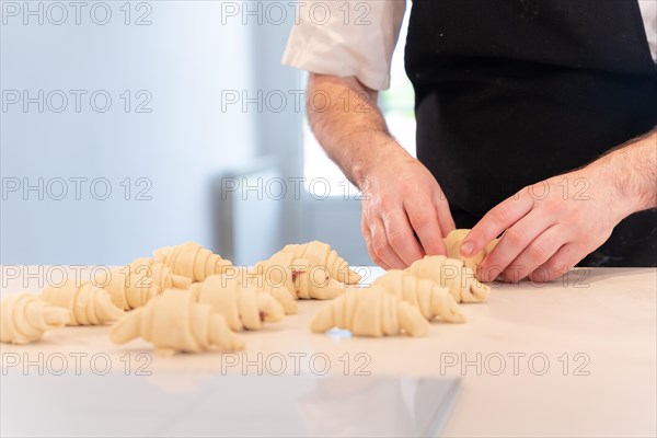 Hands of a man baking small croissants at home