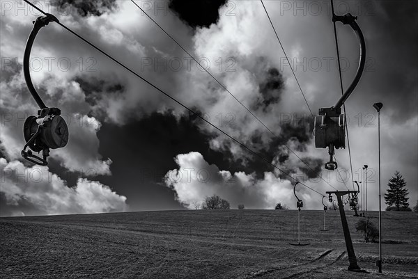 Ski lift at standstill due to lack of snow caused by climate change at the end of winter on a hill in Muensingen