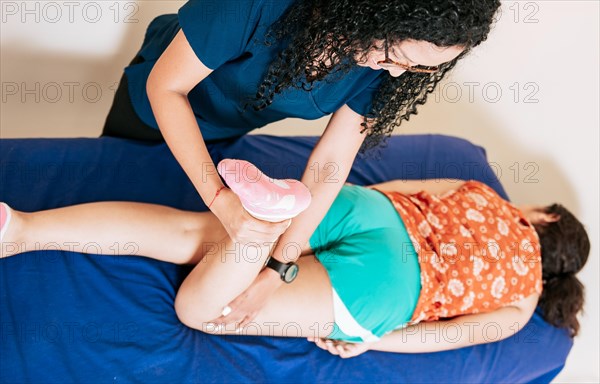 Top view of Chiropractor stretching knee to lying female patient