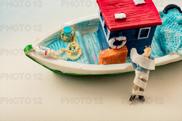 Tiny wrapped figurine of man model beside a model boat