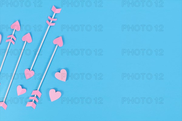 Pink cupid's arrows with heart shaped tips on blue background with copy space