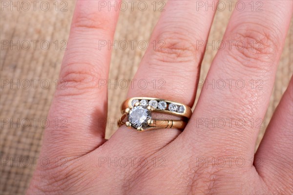 Hand wearing a fake diamond ring on a textured background