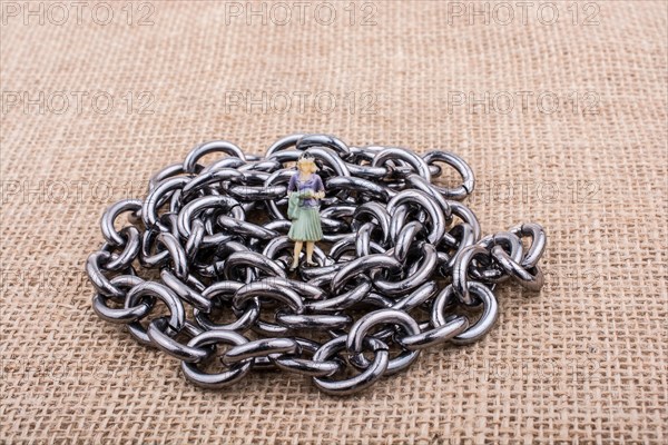 Woman figurine on steel chains on a textured surface on display