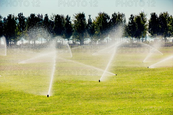 Lawn water sprinkler spraying water over grass in garden