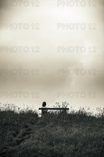 Bench and mountaineer and dramatic clouds in the background