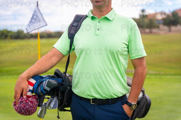 A male golfer walking down the fairway carrying bags