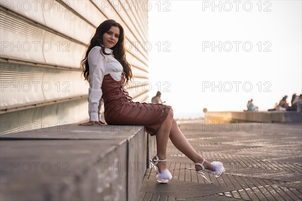 Portrait of a pretty brunette latin woman in a leather skirt sitting in the city on a sunset
