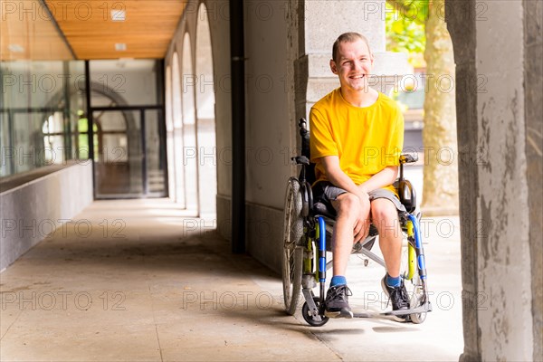 Portrait of a disabled person in a wheelchair smiling next to some columns in a doorway