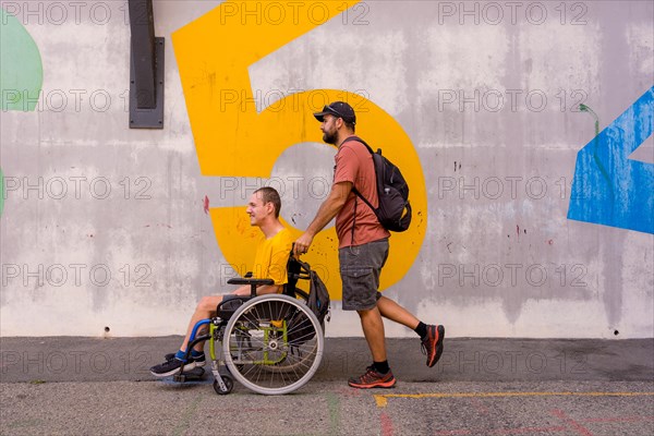 Disabled person in a wheelchair by a cement wall