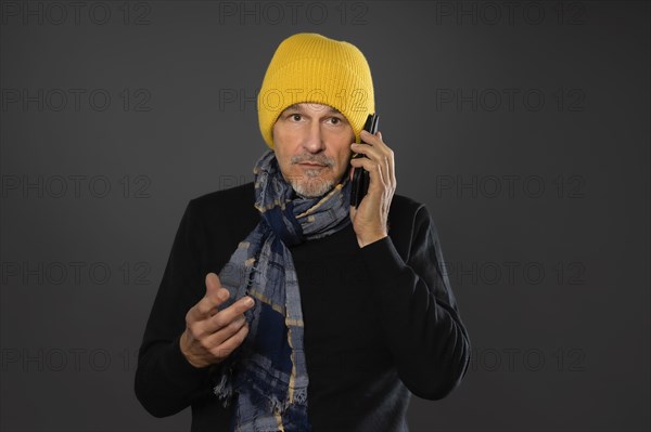 Elderly man with yellow cap on the phone