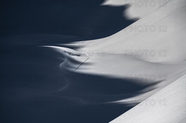 Ski touring trail in deep snowy mountain landscape with light and shadow