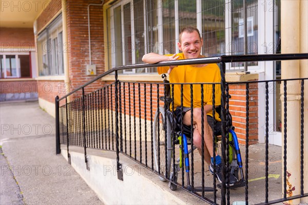 Portrait of a disabled person dressed in yellow in a wheelchair at school smiling