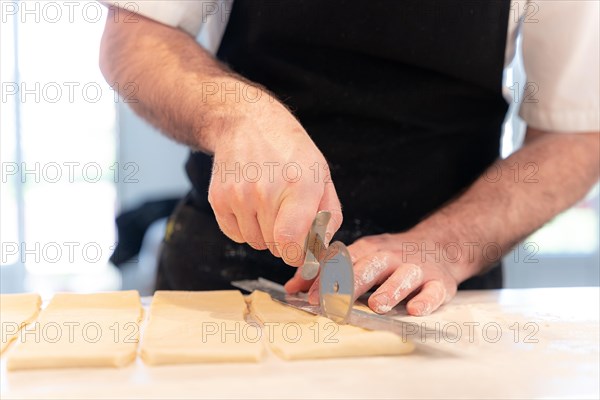 Detail of the hands of a man baking croissants