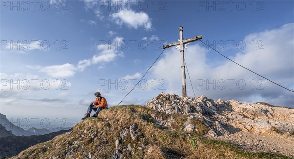 Hiker at the summit of Schartschrofen with summit cross