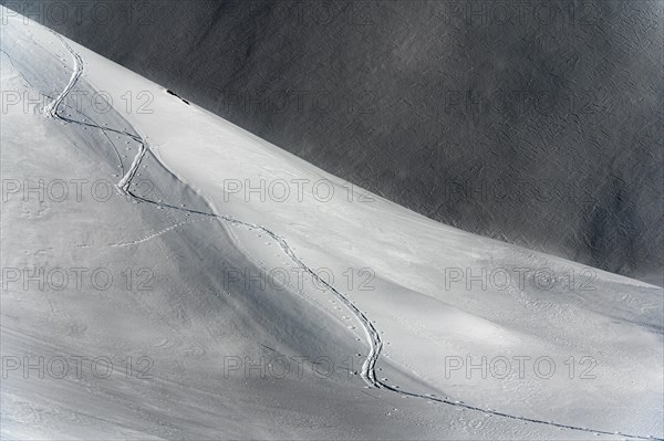 Ski touring trail in deep snowy mountain landscape with light and shadow