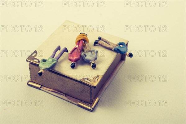 Tiny figurine of men model tied in rope beside a book