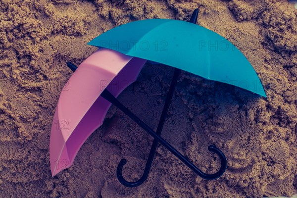Pink umbrella on sand seen from the top