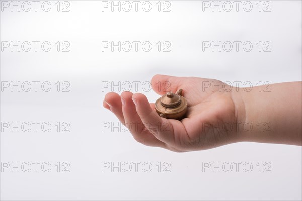 Toddler holding a miniature bronze teapot in the view