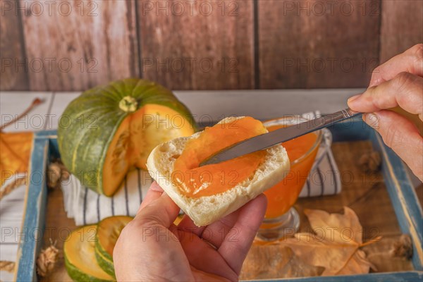 Woman spreading homemade pumpkin jam on a piece of toast with a knife