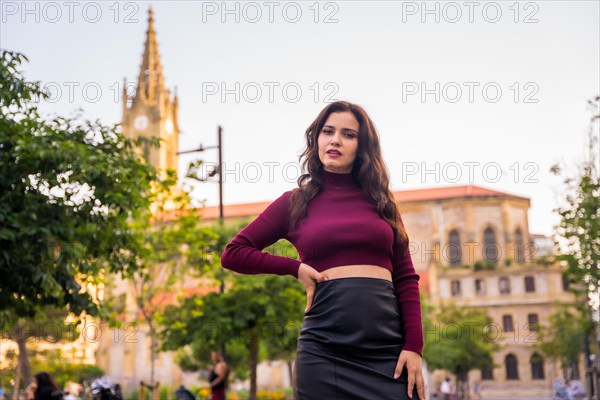 Portrait of a brunette model with a leather skirt next to a church visiting the city