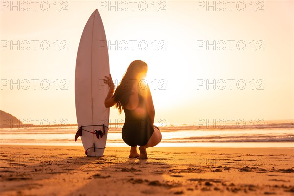 Beautiful surfer woman on the beach at sunset. Bali Indonesia