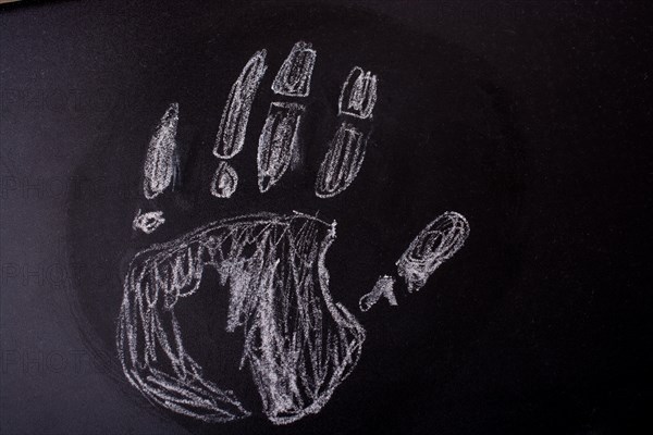 Handprint drawn by white chalk on a blackboard