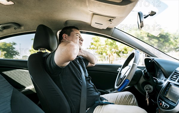 Exhausted driver with pain and stress. Man in the car with neck pain. Exhausted driver with neck pain in traffic