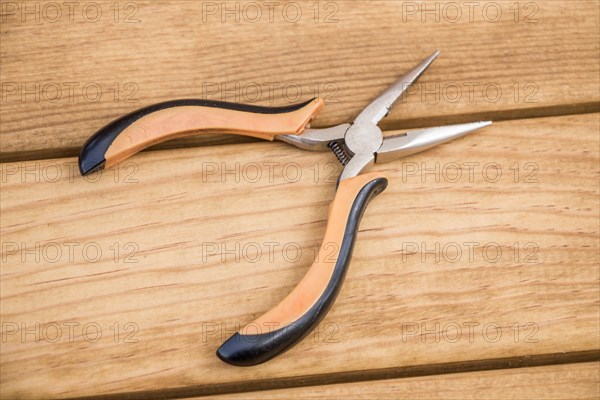 Pincer with plastic handle on a wooden background
