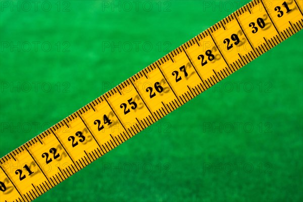 Yellow color measuring tape on green grass