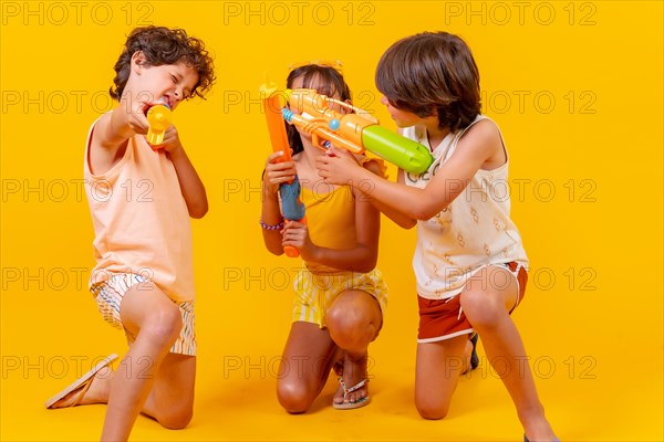 Kids having fun with water pistols on summer vacations and aiming at camera