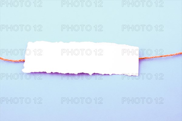 White color note paper placed on a string on a white background