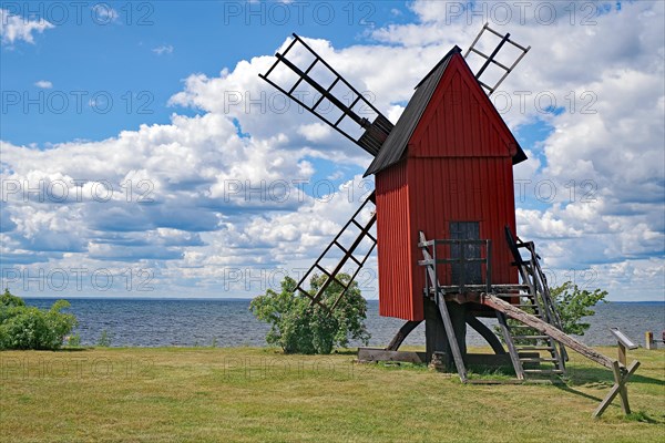 A windmill in a meadow by the sea