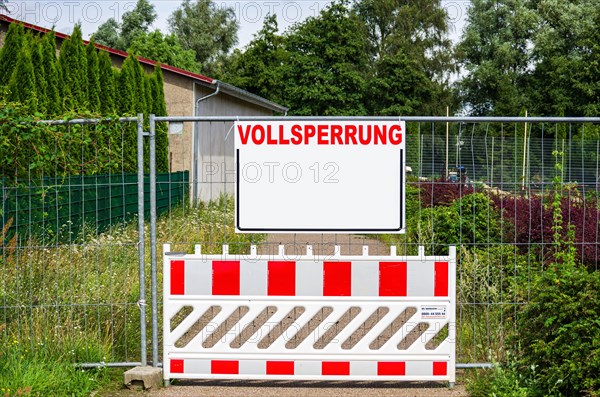 A closed path with a barrier and a construction fence with a rectangular board with a lot of text space with the word FULL CLOSURE