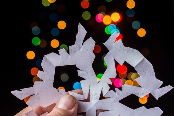 Snowflake shaped paper in hand on bokeh light background