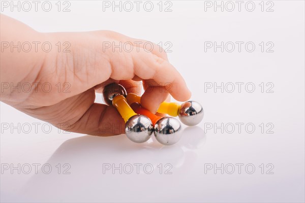 Hand holding magnet toy bars and magnetic balls on a white background