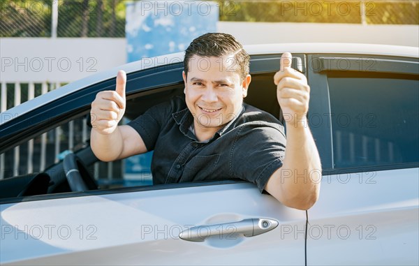 Happy driver giving a thumbs up on the road. safe driving concept. Satisfied driver man showing thumb up. Young driver man in the car showing thumb up