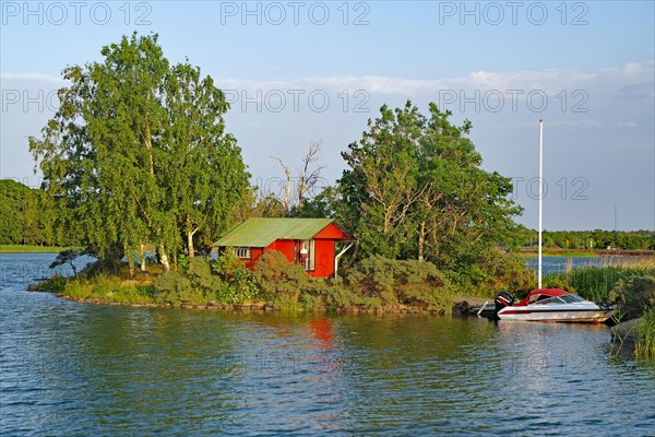 Small red cottage with boat on an island